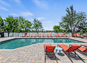 Thumbnail 29 of 52 - A pool area with red chairs and a clear blue sky.