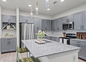 Thumbnail 20 of 20 - A kitchen with a granite countertop and grey cabinets.