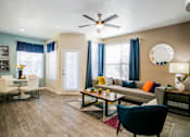 Thumbnail 2 of 44 - A living room with a grey couch, a blue chair and a wooden floor.
