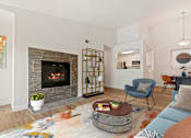 Thumbnail 15 of 55 - A living room with a fireplace and a chair.