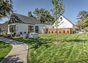 Thumbnail 21 of 29 - A white house with a black roof and a tree in front.