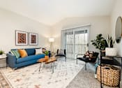 Thumbnail 22 of 48 - Living room with blue sofa and accent chairs at Canyon Creek Apartments, Wilsonville