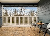 Thumbnail 26 of 48 - Covered balcony with seating and tree views at Canyon Creek Apartments, Wilsonville, OR