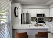 Thumbnail 14 of 18 - A modern kitchen with white cabinets and a large island.