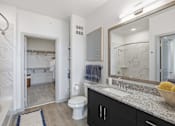 Thumbnail 44 of 55 - A bathroom with a toilet, sink, mirror, and a walk-in shower.