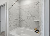 Thumbnail 21 of 55 - A white bathroom with a marble tile wall and a white bathtub.
