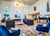 Thumbnail 23 of 44 - A living room with a blue chair and a colorful rug.