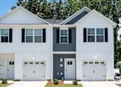 Thumbnail 13 of 15 - A two-story house with white and grey exterior and two garages.