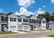 Thumbnail 15 of 15 - A row of houses with garages and driveways.