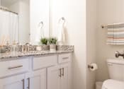 Thumbnail 11 of 15 - A white bathroom with a toilet, sink, and mirror.