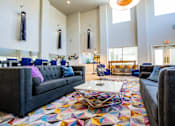 Thumbnail 24 of 44 - A large room with a grey couch and a colorful rug.
