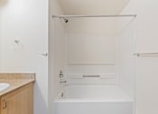 Thumbnail 33 of 36 - A white bathroom with a tub and sink.