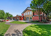 Thumbnail 35 of 52 - A building with a red and brown exterior is surrounded by a grassy area and a paved walkway.