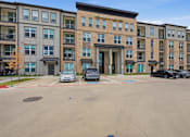 Thumbnail 16 of 55 - A parking lot in front of a multi-story apartment building.