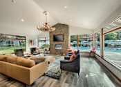 Thumbnail 30 of 48 - Clubhouse seating area with stone fireplace and pool views at Canyon Creek Apartments, Wilsonville, OR 97070