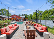Thumbnail 25 of 52 - A patio with red couches and a fire pit.