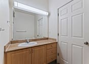 Thumbnail 24 of 36 - A bathroom with a sink, mirror, and wooden cabinets.