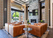 Thumbnail 32 of 48 - A living room with a stone fireplace and a brown leather couch.