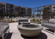 Thumbnail 47 of 59 - a patio with chairs and a fire pit in front of an apartment building at Element 12 Apartments, Henderson NV