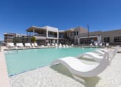 Thumbnail 53 of 59 - a pool with white chairs and a building in the background at Element 12 Apartments, Henderson NV
