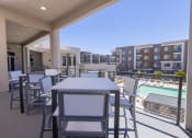 Thumbnail 45 of 59 - a patio with tables and chairs and a swimming pool at Element 12 Apartments, Henderson NV