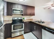 Thumbnail 4 of 27 - Kitchen with stainless steel appliances and wooden cabinets at Ascend2300, Carlsbad, 92008