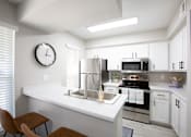 Thumbnail 1 of 18 - A modern kitchen with a stove, sink, and cabinets.