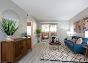 Thumbnail 2 of 18 - A living room with a blue couch and a wooden cabinet.