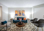 Thumbnail 6 of 18 - A living room with a sofa, chairs, and a coffee table.