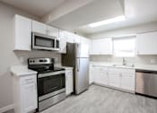 Thumbnail 8 of 18 - A kitchen with white cabinets and stainless steel appliances.