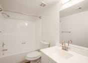 Thumbnail 13 of 18 - A white bathroom with a toilet, sink, and shower.