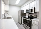 Thumbnail 12 of 18 - A kitchen with a black refrigerator, stove, and oven.