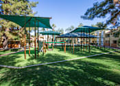 Thumbnail 4 of 18 - A playground with a green canopy and a white rope fence.