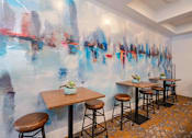 Thumbnail 31 of 48 - A room with a wall mural and a table with four stools.