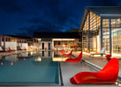 Thumbnail 11 of 26 - a swimming pool at night with red chairs around it