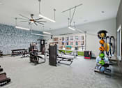 Thumbnail 11 of 55 - A gym with a variety of equipment including weights and a fan.