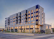Thumbnail 34 of 36 - A modern multi-story building with balconies is illuminated from within.