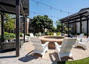 Thumbnail 40 of 48 - A patio with white chairs and a fire pit.