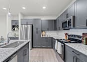 Thumbnail 18 of 20 - A modern kitchen with grey cabinets and a white countertop.