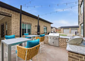 Thumbnail 43 of 55 - A patio with a table and chairs is set up outside a brick building.