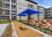 Thumbnail 12 of 55 - A patio area with a blue umbrella and chairs.