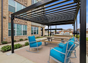 Thumbnail 41 of 55 - A patio with blue chairs and a black metal awning.