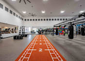 Thumbnail 26 of 48 - A gym with orange mats and weights.