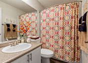 Thumbnail 14 of 33 - Bathroom with decorative shower curtain and tan vanity at Hubbard's Crossing Apartments, Kirkland, Washington