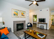 Thumbnail 5 of 44 - A living room with a fireplace, a chair, a coffee table, and a television.
