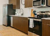 Thumbnail 5 of 12 - A modern kitchen with a stainless steel oven and wooden cabinets.