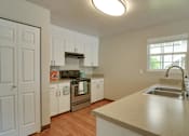 Thumbnail 9 of 30 - A kitchen with white cabinets and a wooden floor.