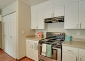 Thumbnail 8 of 30 - A kitchen with white cabinets and a stove top oven.