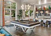 Thumbnail 13 of 28 - A pool table is in the middle of a room with a blue couch.
