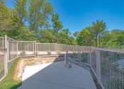 Thumbnail 31 of 35 - a park with a fenced in area with trees and a retaining wall